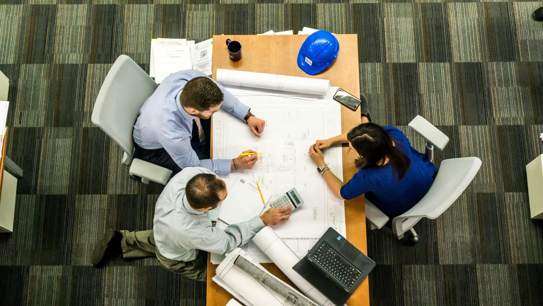 Vue de dessus d'une équipe travaillant sur des plans de construction dans un bureau.